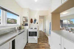 帕拉帕拉乌姆海滩The Green Trout - Paraparaumu Beach Holiday Home的厨房配有白色橱柜和炉灶烤箱。