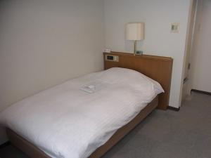 山形市新最上屋酒店的一张小床,放在一个房间里,上面有灯