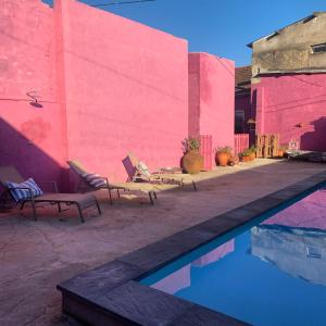 圣塔伦São Miguel House , Casa do Carvalhal的一个带两把椅子和粉红色墙壁的游泳池