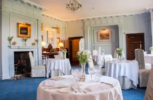 Bronllys朗格伊德大厅酒店的一间设有白色桌椅和壁炉的用餐室