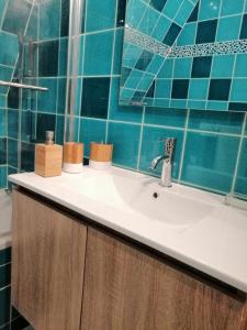 多维尔Magnifique deux pièces au calme的浴室配有水槽和蓝色瓷砖墙。