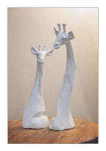 温特和克Felzarette Self Catering Apartment 7的木桌旁的两件长颈鹿雕塑