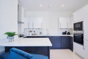 伦敦宫殿码头公寓的厨房配有白色橱柜和蓝色椅子