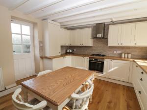 林肯Farriers Cottage的厨房配有木桌和白色橱柜。