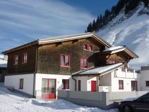 丰塔内拉Haus Emilia am Faschinajoch的雪中带红色窗户的房子