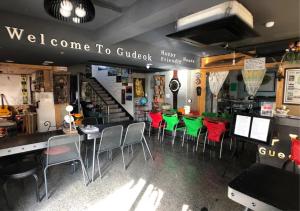 西归浦市古多克旅馆的餐厅设有红色和绿色的椅子和柜台