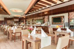 乌沙克华美达乌沙克酒店的一间带木桌椅的餐厅和一间酒吧