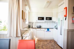 哥德堡Lisebergsbyns Vandrarhem的厨房配有白色橱柜和红色椅子