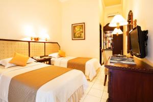 马格朗Puri Asri Hotel & Resort的酒店客房设有两张床和一台平面电视。