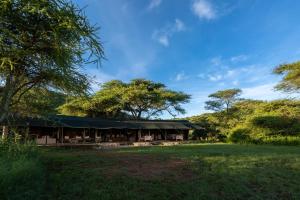 塞伦盖蒂Serengeti Woodlands Camp的一座在田野上拥有绿色屋顶的建筑