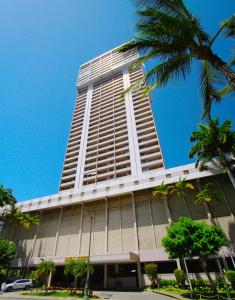檀香山Royal Kuhio Resort的一座高大的建筑,前面有一棵棕榈树