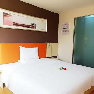 金昌7天酒店·金昌文化街店的卧室配有白色的床,上面有红玫瑰