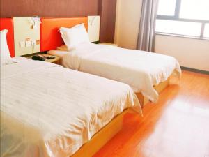 金昌7天酒店·金昌文化街店的配有白色床单的酒店客房内的两张床