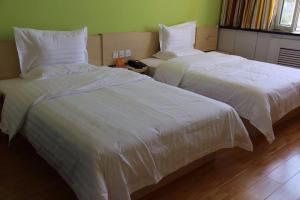 哈密7天酒店·哈密宝丰市场店的客房内的两张床和白色床单