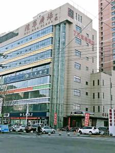 石家庄7天酒店·石家庄友谊大街建国路店的一座大型建筑,前面有汽车停放