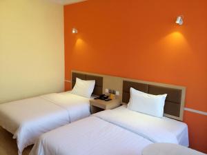 哈尔滨7天酒店·哈尔滨火车站南广场店的橙色墙壁的客房内的两张床