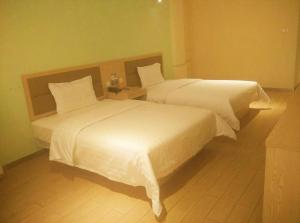 哈尔滨7天酒店·哈尔滨火车站南广场店的配有白色床单的酒店客房内的两张床