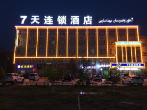 Wensu7天酒店·阿克苏机场店的停车场内有灯光标志的建筑物