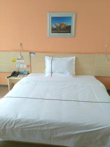 Wensu7天酒店·阿克苏机场店的卧室里一张大白色的床,有橙色的墙壁