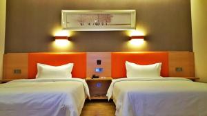 涪陵7天优品·重庆涪陵滨江大道店的酒店客房设有两张床和橙色的墙壁。