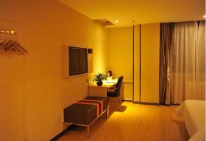 石嘴山7天优品·石嘴山大武口店的酒店客房设有一张桌子和一台墙上的电视。