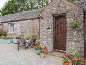 MorlandRosegarth Cottage的石头建筑,有木门和鲜花