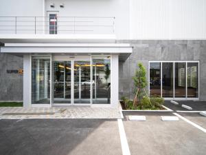 川越Super Hotel Saitama Kawagoe的停车场内有玻璃门的建筑