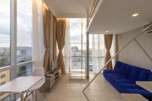 马尼拉Selah Pods Hotel Manila的客厅设有蓝色的沙发和大窗户