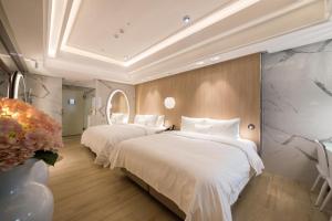 Xinwu悠悦旅馆的配有白色床单的酒店客房内的两张床