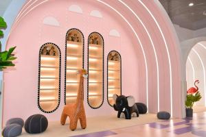 上海上海三甲港绿地铂骊酒店-提供浦东机场和迪士尼班车的一间设有长颈鹿和大象的粉红色墙壁的房间
