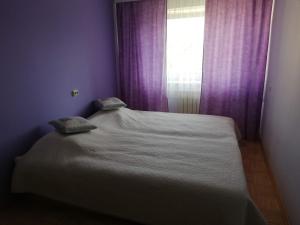凯尔德拉Vabaduse Apartment的一张位于带紫色窗帘窗户的房间里的床