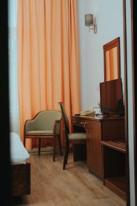 奥西耶克Hotel Central的橙色窗帘、书桌和椅子的房间