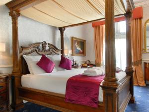 伦敦Grand Royale Hyde Park的一间卧室配有一张带紫色枕头的天蓬床