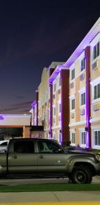 达拉斯达拉斯爱田贝蒙特旅馆套房酒店的停在一座紫色灯的建筑前面的卡车