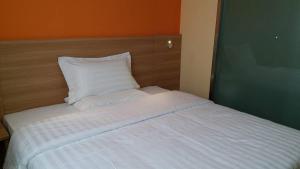 哈尔滨7天酒店·哈尔滨先锋路禧龙大市场店的一张带白色床单和枕头的床