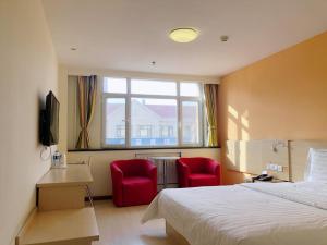 天津7天酒店·天津武清高铁站尚东金街店的酒店客房,配有一张床和两张红色椅子