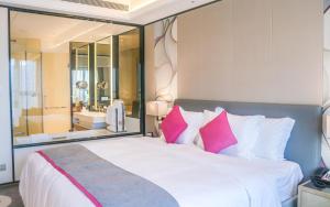 杭州杭州钱塘皇冠假日酒店的卧室配有带粉红色枕头的大型白色床