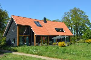 德尔宁恩Erve Grootenhuys的绿色田野上一座带橙色屋顶的房子