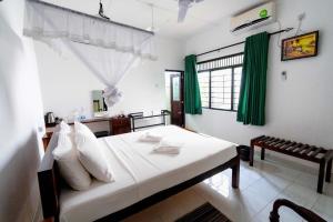 阿努拉德普勒Water Front Home Stay的一间卧室配有白色床单和绿色窗帘
