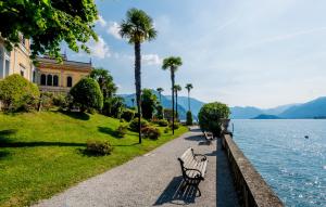 贝拉吉奥Grand Hotel Villa Serbelloni - 150 Years of Grandeur的排在水体旁边的一排公园长椅