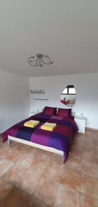 SonognoCasa 21的一间卧室配有一张大床,提供紫色床单和枕头