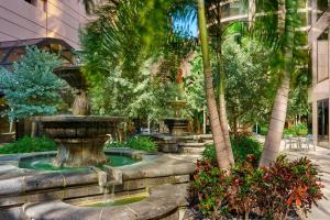 坦帕坦帕西海岸翠贡精选酒店的一座树木繁茂的建筑前的喷泉