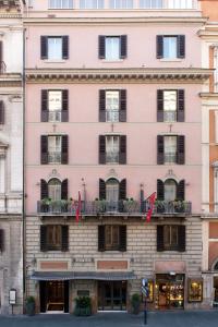 罗马马斯卡尼酒店的粉红色的建筑,设有黑窗和阳台
