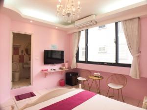 吉安花莲大碗民宿的粉红色的卧室,配有一张床和两把椅子