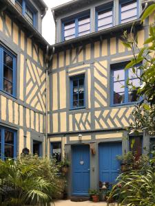 翁弗勒尔Reglisse et Pain d'Epices - Chambres d'hôtes的一座带蓝色门窗的旧房子