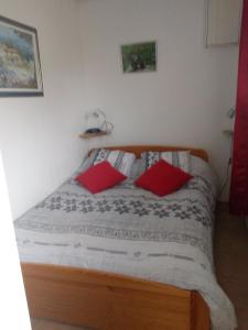 Saint-Laurent-du-CrosLa Collinette的一间卧室配有一张带两个红色枕头的床