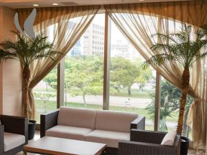 那霸Almont Hotel Naha Omoromachi的带沙发和两棵棕榈树的客厅