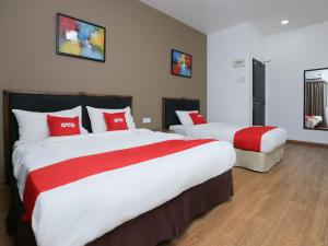 龟咯OYO 89915 East Mount Hotel的两张位于酒店客房的床铺,配有红色枕头