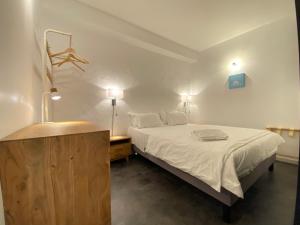 巴约讷Boutique Hôtel Un Appart en Ville的卧室配有白色的床和木制梳妆台。