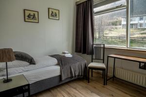 Bíldudalur海港住宿加早餐旅馆的一间卧室配有一张床、一张书桌和一个窗户。